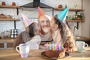 Dark-skinned girls celebrating his granddads bithday and kissing him on cheeks