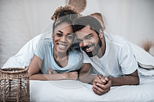 Dark skinned husband and wife lying on bed