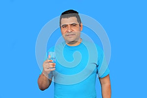 Dark-skinned Latino adult man shows his glass with water to hydrate himself in hot weather photo