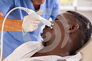 Dark-skinned patient receiving cosmetic facial radiofrequency procedure