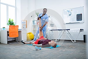 Dark-skinned therapist working with patient in spacious clinics