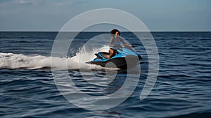 A dark-skinned young woman in a swimsuit rides a jet ski on the blue sea