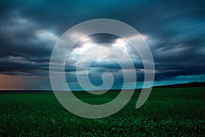 Dark sky with rain clouds over green field