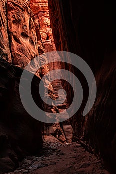 Dark Slot Canyon With A Bright Orange Wall In The Background