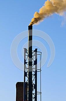 Dark smoke from a chimney against blue sky