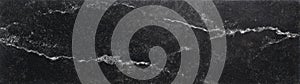 Dark soapstone marble surface with diagonal white mineral lines and subtle speckles photo