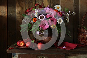 dark still life with a bouquet of garden flowers in a clay jug.