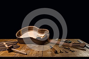 Dark still life of luthie's workbench. Guitar in unfinished construction. dark black background