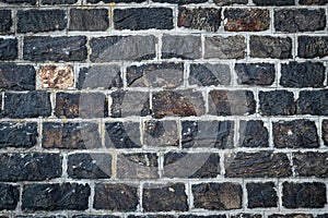Dark stone wall background. Old black brick texture, rock floor pattern. Construction natural material, vintage granite, grunge