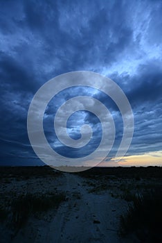 Dark storm clouds above sand road in steppe