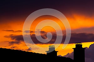 Dark storm clouds during sunset and silhouette of chimney with dramatic sky and vibrant colors