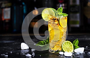 Dark and Stormy alcoholic cocktail drink with dark rum, ginger ale, lime and ice, black bar counter background