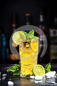 Dark and Stormy alcoholic cocktail drink with dark rum, ginger ale, lime and ice, black bar counter background