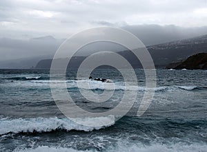 Dark stormy atlantic ocean waves breaking on rock and the beach