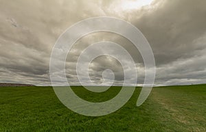 Dark stormy clouds over a green grass field