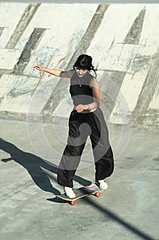 Dark style skater girl doing slalom on skate park