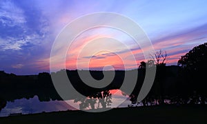 Dark sunset with crimson clouds. Twilight over lake. Dusk above river