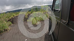 A dark SUV is driving on a rocky road while traveling in the mountains. A military vehicle drives patrolling a difficult