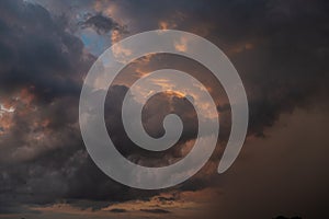 A dark thundercloud on the background of sunset