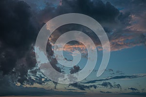 a dark thundercloud on the background of sunset