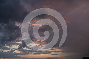 A dark thundercloud on the background of sunset