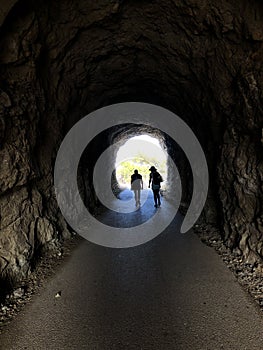 Dark Tunel with two people walking inside in the dark photo