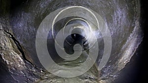 Dark underground sewer round concrete tunnel. Industrial wastewater and urban sewage flowing throw sewer pipe