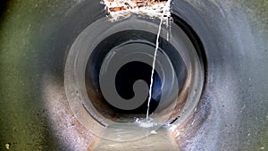 Dark underground sewer round concrete tunnel. Industrial wastewater and urban sewage flowing throw sewer pipe