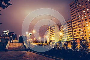 Dark urban alley at night with street lamps and houses