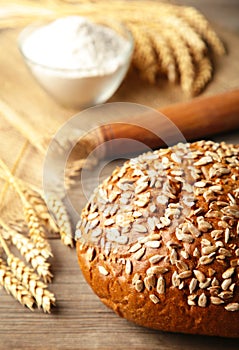 Dark whole grain bread with seeds and spikelet of wheat on grey background. Vertical foto