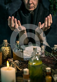 Dark Witch at work: black magic woman makes the witchery by mixing herbs, casting the spells, running magic rituals