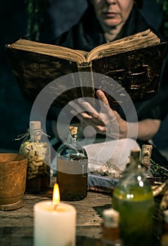 Dark Witch at work: black magic woman makes the witchery by mixing herbs, casting the spells, running magic rituals