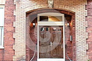 A dark wood stained double door entrance on a red brick building