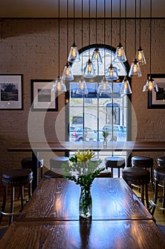 Dark wood table with fresh cut flowers and edison pendant lights