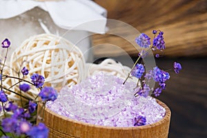 On a dark wooden background, purple bath salt, for relaxation, in a jar, with flowers for fragrance, close-up
