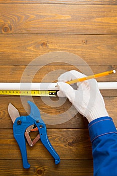 On a dark wooden background, the workerâ€™s hands in white gloves, measure the desired size with a pencil, for cuts, there is a
