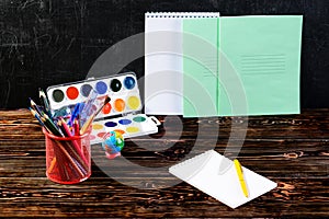 Dark wooden table with pencil holder, colorful pencils, notebook