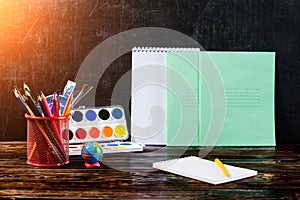 Dark wooden table with pencil holder, colorful pencils, notebook