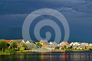 Lakeside holiday resort by dark-blue sky at sunset and imminent storm