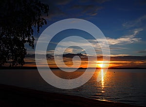 Darkening sunset sky over the lake with colorful clouds, Golden hour