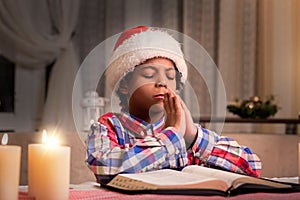 Darkskinned boy praying on Christmas.