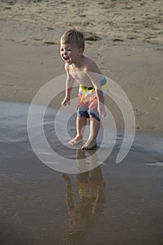 Darling boy happy facial expression at the beach standing in the