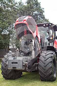 Large new red tractor with bonnet up showing engine in field