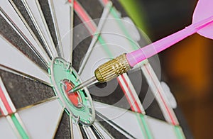 Dart arrow hitting in the target center of dartboard