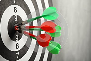 Dart board with arrows hitting target on grey wall,