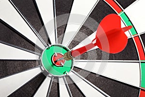 Dart board with red arrow hitting target,