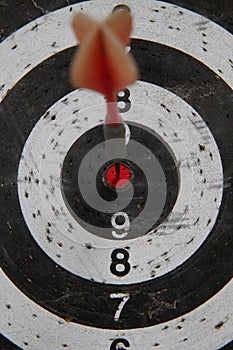 Dart board with red arrow hitting target right in bullseye