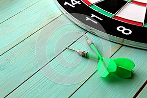 Dart board with two darts lies on a wooden background