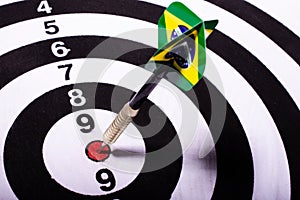 Dart with Brazil flag spiked in the center of black and white target. Selective focus