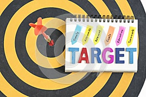 Dart target in bullseye with words target on the notebook with h